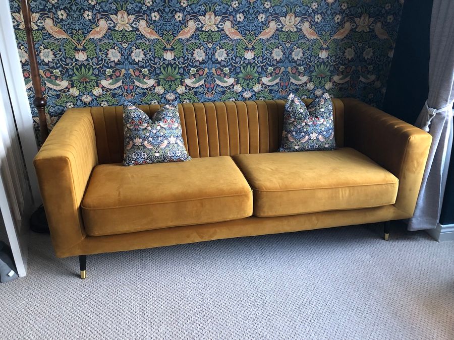 Slender mustard sofa with stitching on the backrest