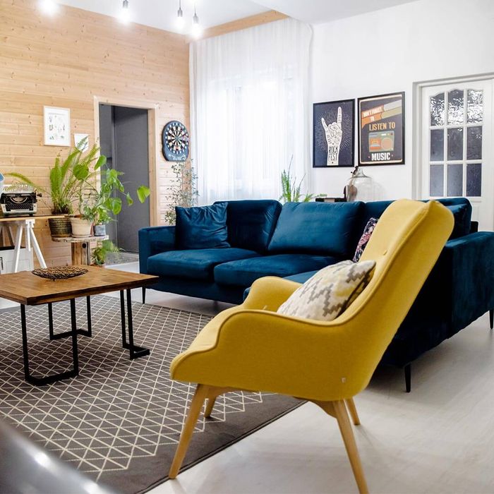 Fauteuil à oreilles jaune Ducon et canapé d'angle bleu foncé Covex
